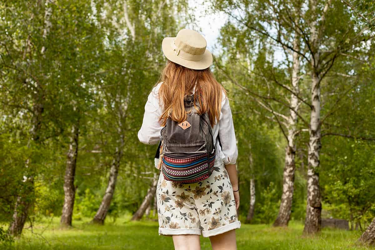 Girl with a hat and backpack walking in the nature.