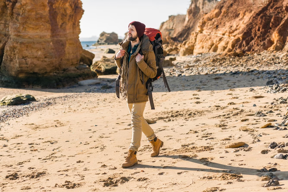A man with a large backpack traveling on the beach.